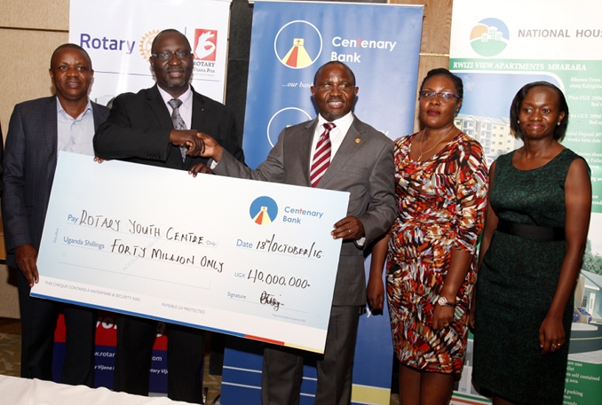 Centenary Bank MD Fabian Kasi (3R) hands over a dummy cheque to Rotary Club of Kampala North Past District Governor Robert Waggwa Nsibirwa at the bank's offices on Tuesday. Looking on is Centenary Bank Brand & Marketing Manager Immaculate Ngulumi and Chief Manager Corporate Affairs Allen Ayebare (R).