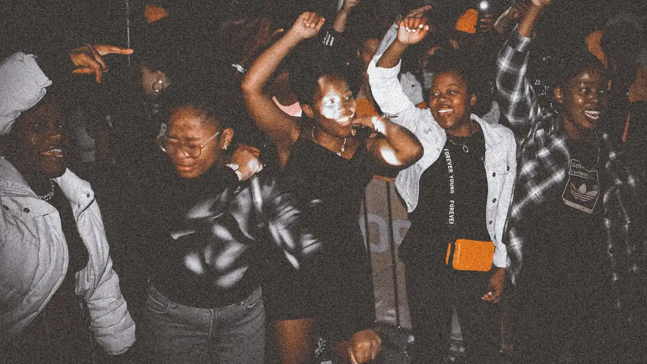 A group of young people dancing at a crowded nighttime event.
