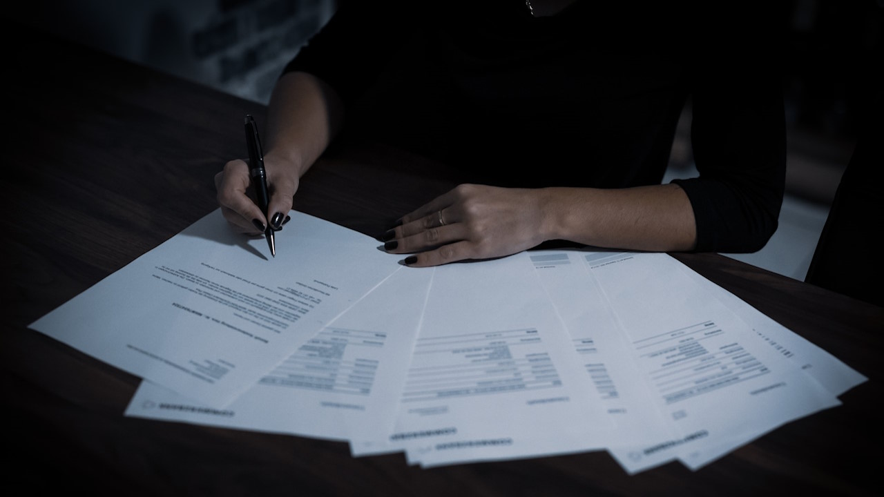 A woman signing a contract with a ballpoint pen