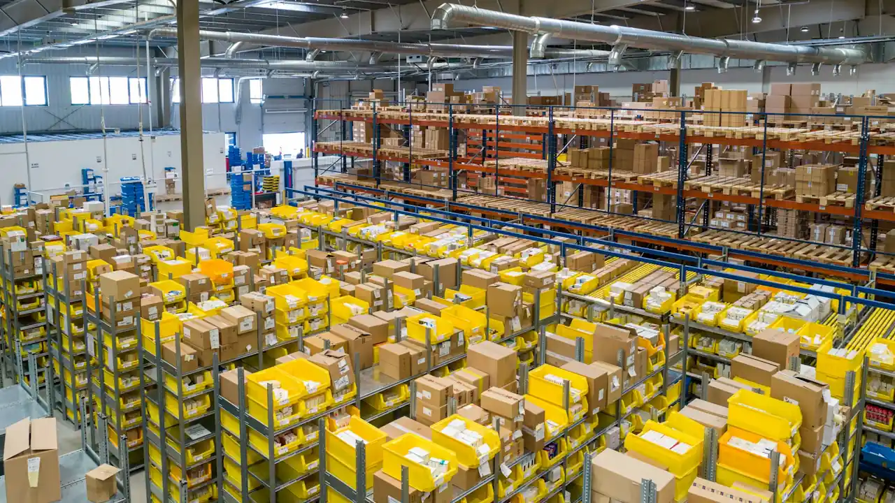 High-angle view of an expansive industrial warehouse showing systematic stock accumulation in yellow bins and tiered racking.