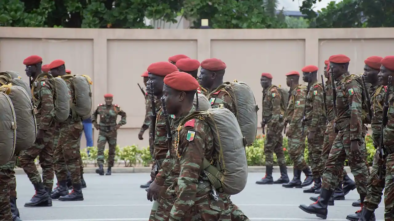 Beninese soldiers in camouflage uniforms and red berets stand in formation during a military parade at independence day celebrations in Benin, 2024.