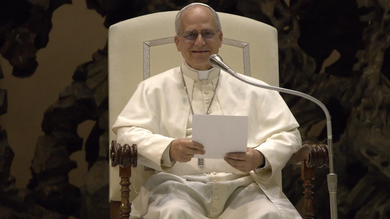 A man wearing a white cassock and zucchetto sits in a high-backed chair while holding a sheet of paper.