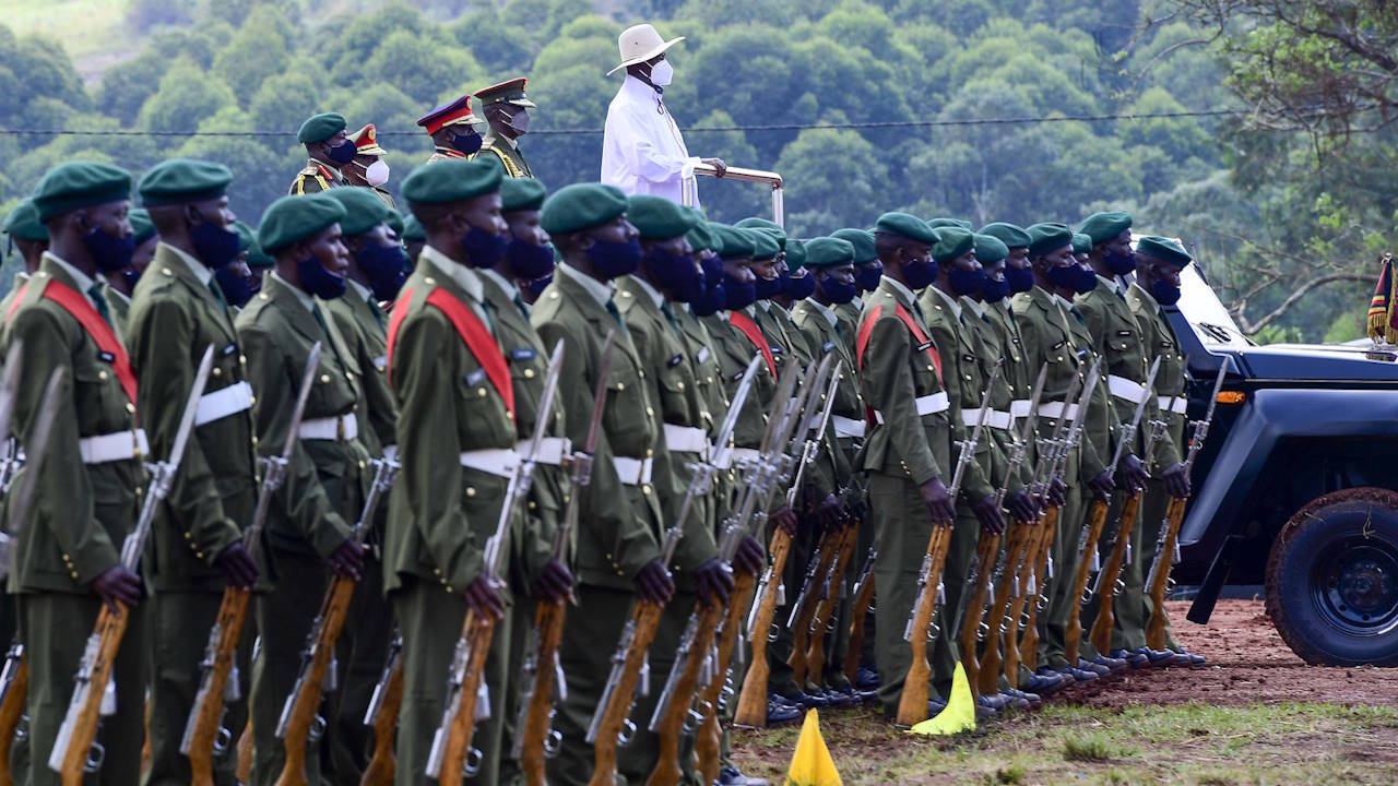 Uganda's President Museveni atop a military pickup, inspecting an honour guard, four top security officers standing behind him