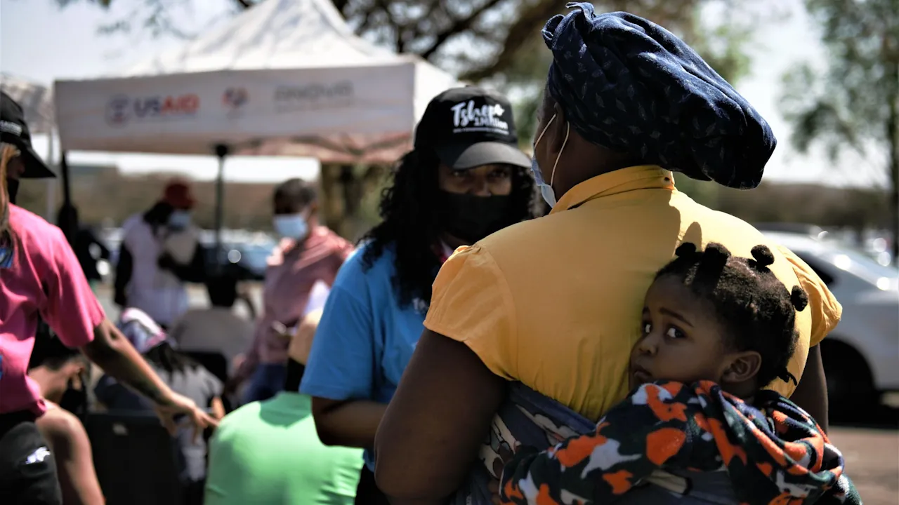 A mother, carrying a baby on her back, getting a vaccine from a USAID mobile clinic in South Africa