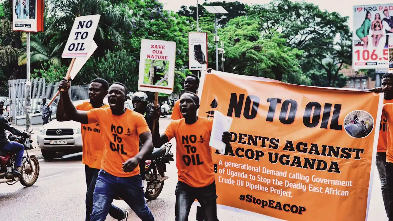 Male student activists holding banners and placards bearing anti-fossil fuel and anti-East African Crude Oil Pipeline Project messages march through the streets of Kampala.