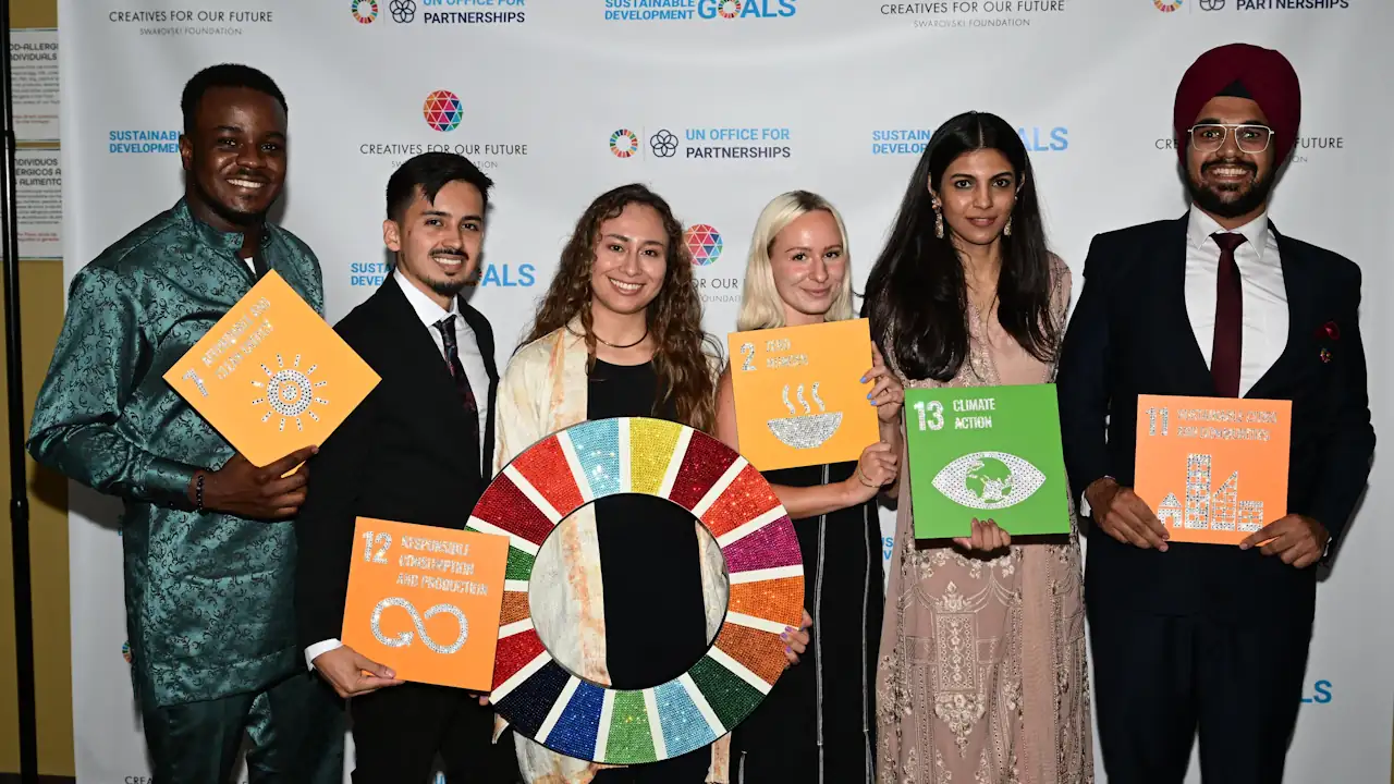 A group photo of the 2023 Creatives for Our Future cohort. It shows three men and three women from different parts of the world standing in front of a white banner.