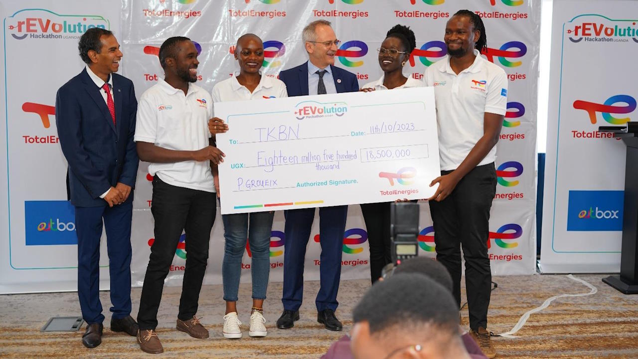 Six people on at an awards ceremony, holding a dummy cheque